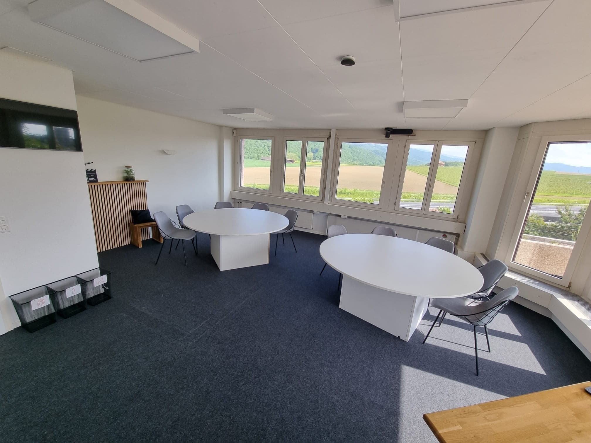 Vue de la salle Fléchettes depuis l’entrée, tables rondes et coin bois